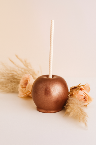 Goldene Zuckerapfel-Dekoration mit Blüten und Sträuchern im Hintergrund.