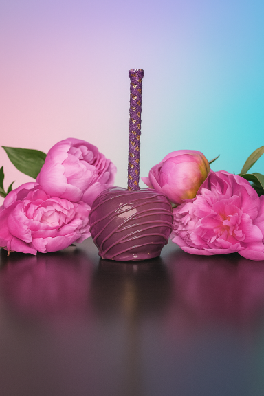 Lila Zuckerapfel umgeben von rosa Pfingstrosen auf einem dunklen Hintergrund.