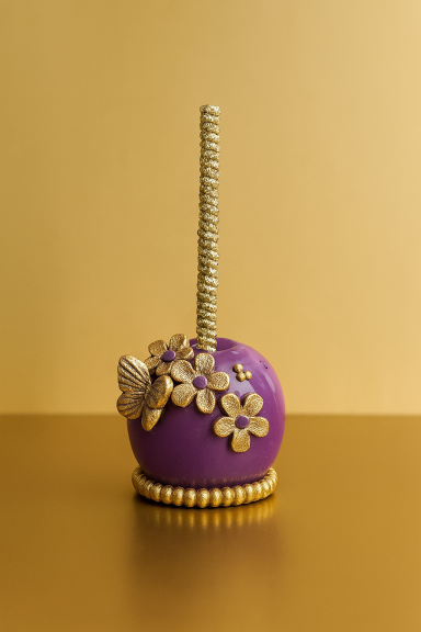 Violette Süßigkeit mit goldenen Verzierungen und einem Stab auf goldenem Hintergrund.